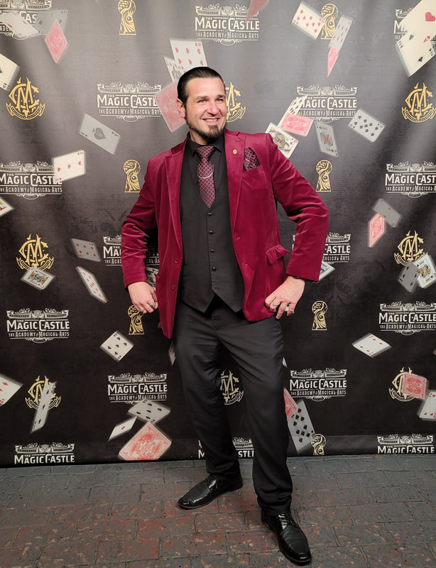 Magician Matthew King standing in front of the Magic Castle banner in Hollywood.
