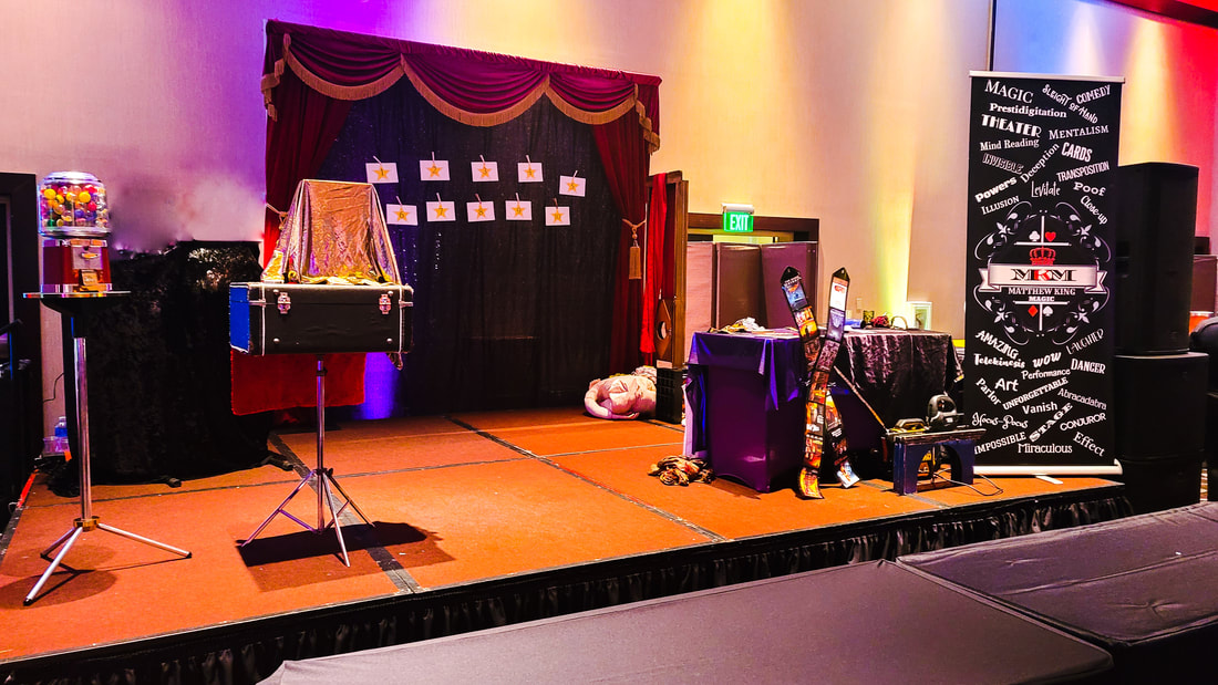 San Diego Magician Matthew King's stage show with theater curtains, gumball machine, banner, and magic props