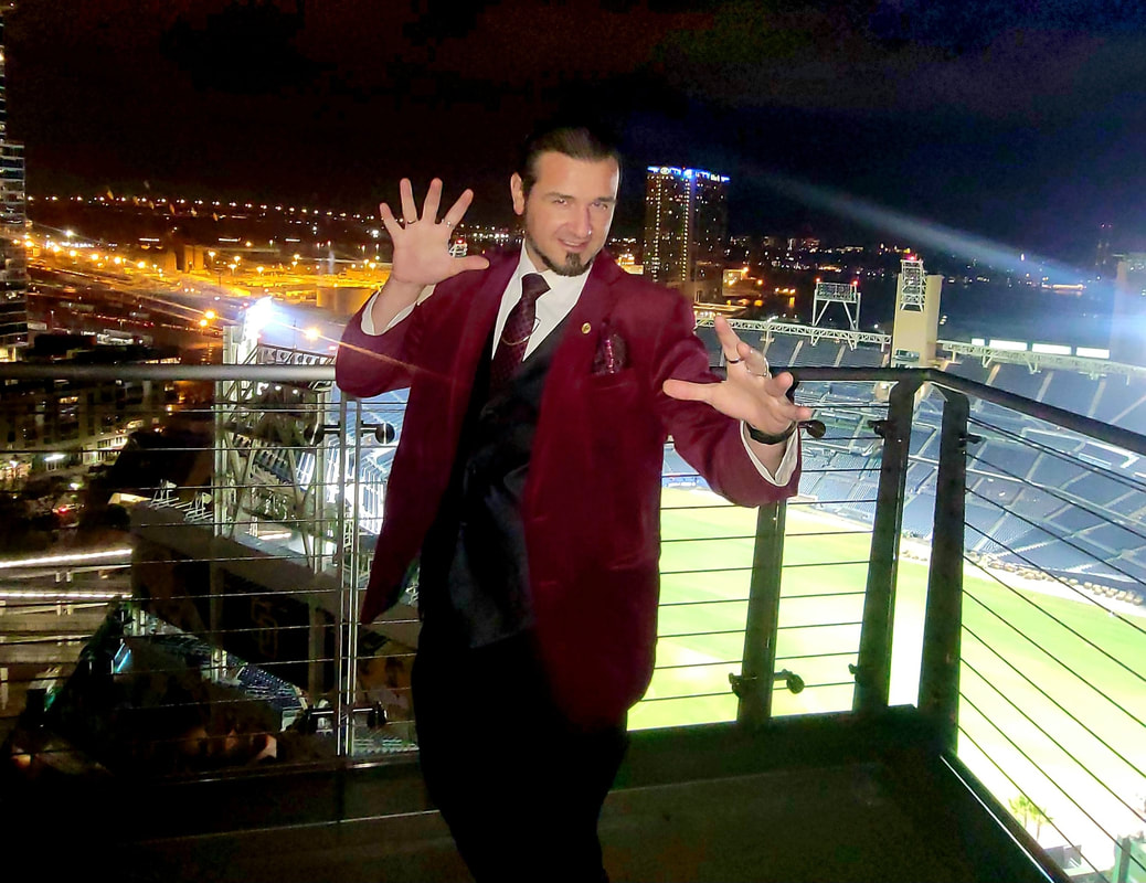 San Diego corporate magician Matthew King at The Skybox above Petco Park in front of San Diego skyline performing strolling magic.